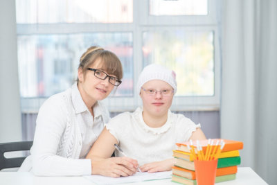 portrait of happy teacher and girl with down syndrome